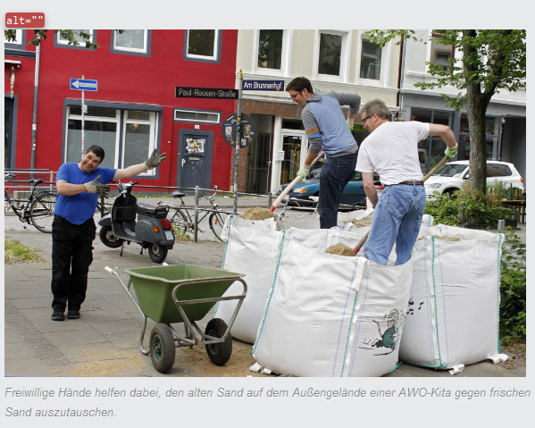 Tatkräftige Helfer: Drei männliche Helfer stehen mit Schaufeln, Schubkarre und Sandsäcken auf dem Außengelände einer AWO-Kita und tauschen alten Sand gegen neuen aus.