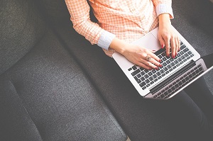 Eine Frau sitzt mit einem Laptop auf dem Sofa